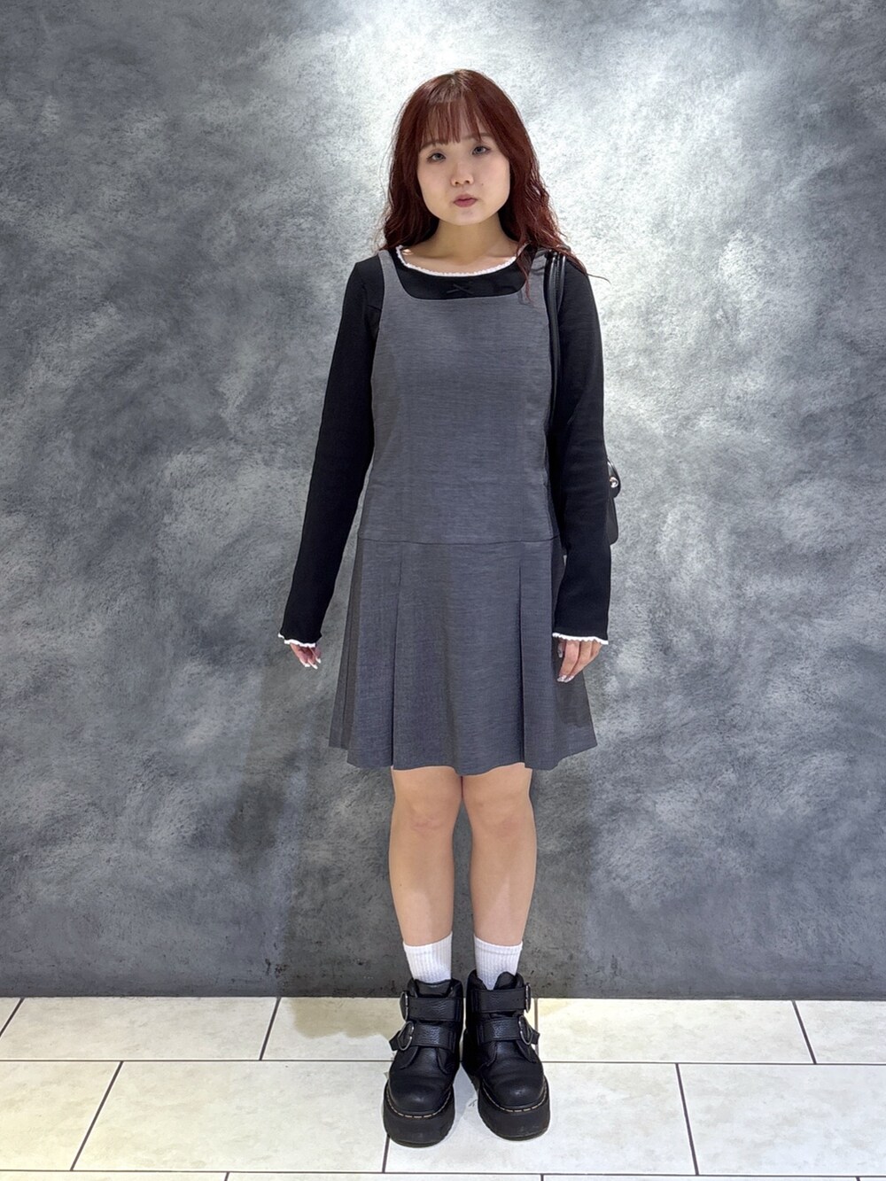 ブラック系のTシャツ/カットソー、ブラック系のブーツ、グレー系のジャンパースカートを着用したレディースの秋コーディネートの2枚目の写真