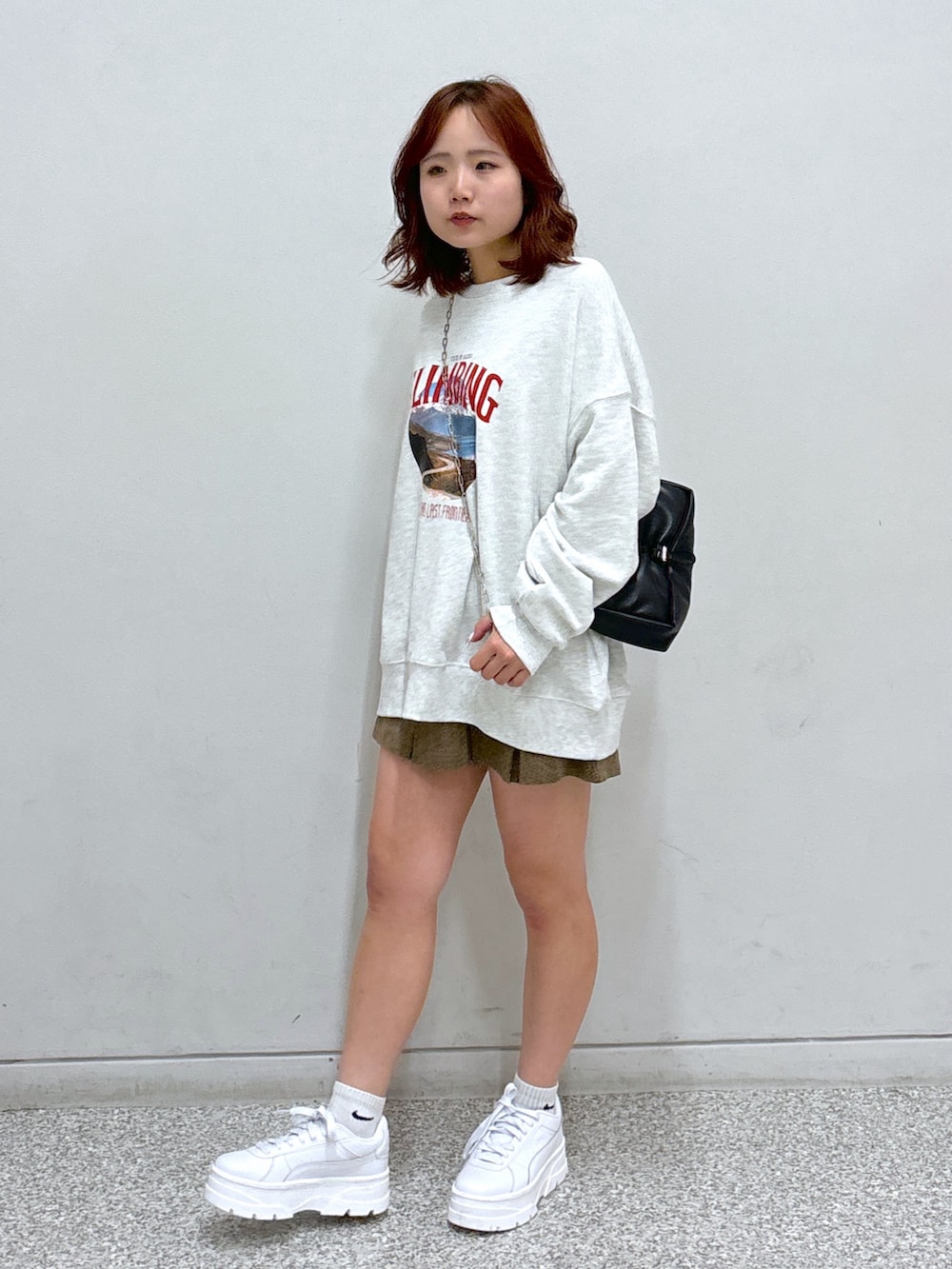 ホワイト系のスウェット、ブラウン系のスカート、ブラック系のハンドバッグを着用したレディースの秋コーディネートの2枚目の写真