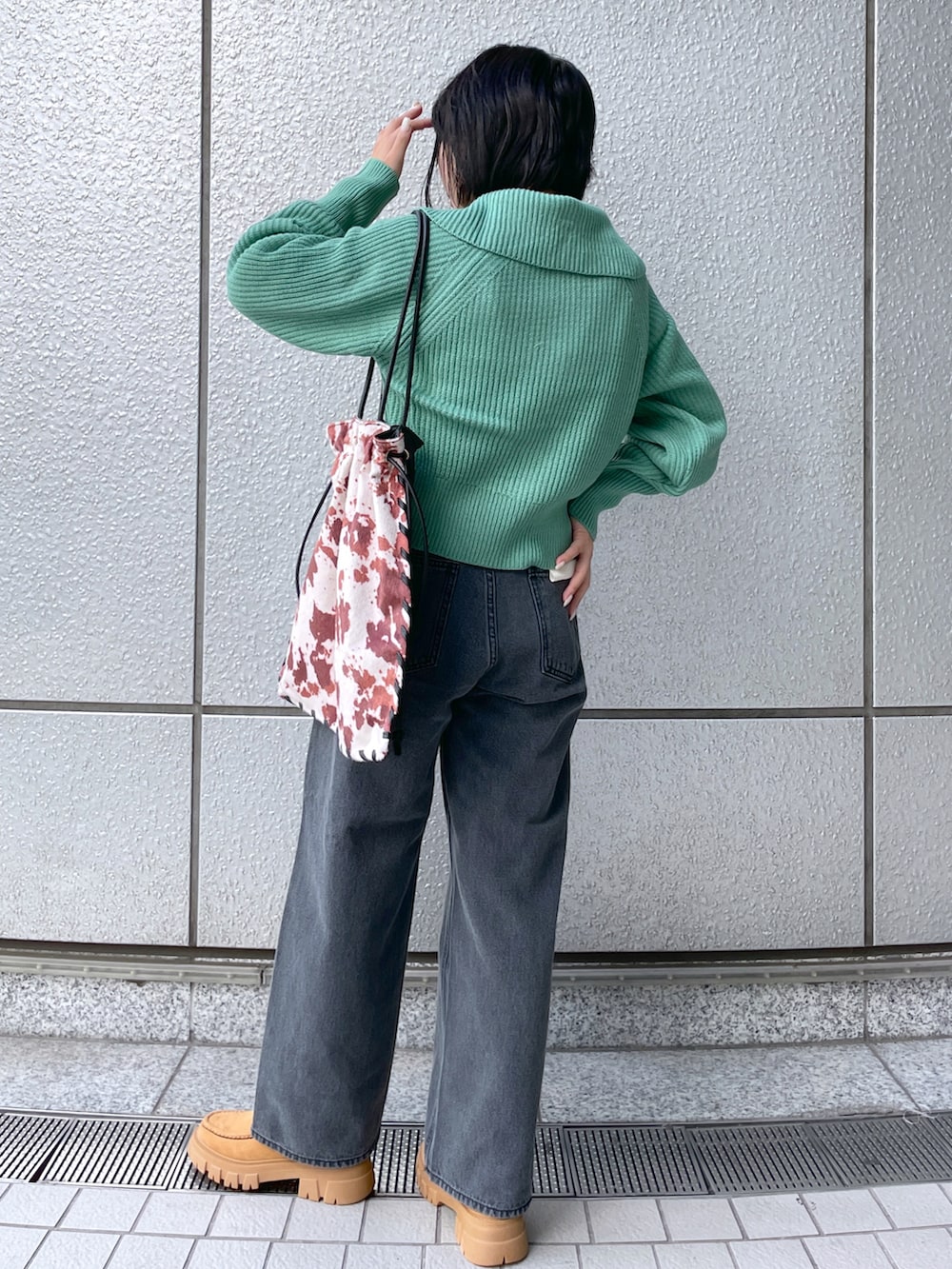 ブラック系のデニムパンツ、グリーン系のカーディガン/ボレロ、ブラウン系のブーツを着用したレディースの秋コーディネートの2枚目の写真