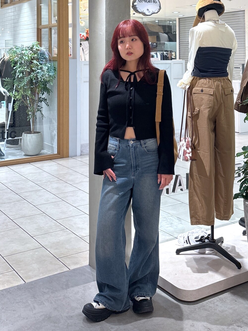 ブラック系のニット/セーター、ホワイト系のキャミソール、ブルー系のデニムパンツを着用したレディースの秋コーディネートの2枚目の写真