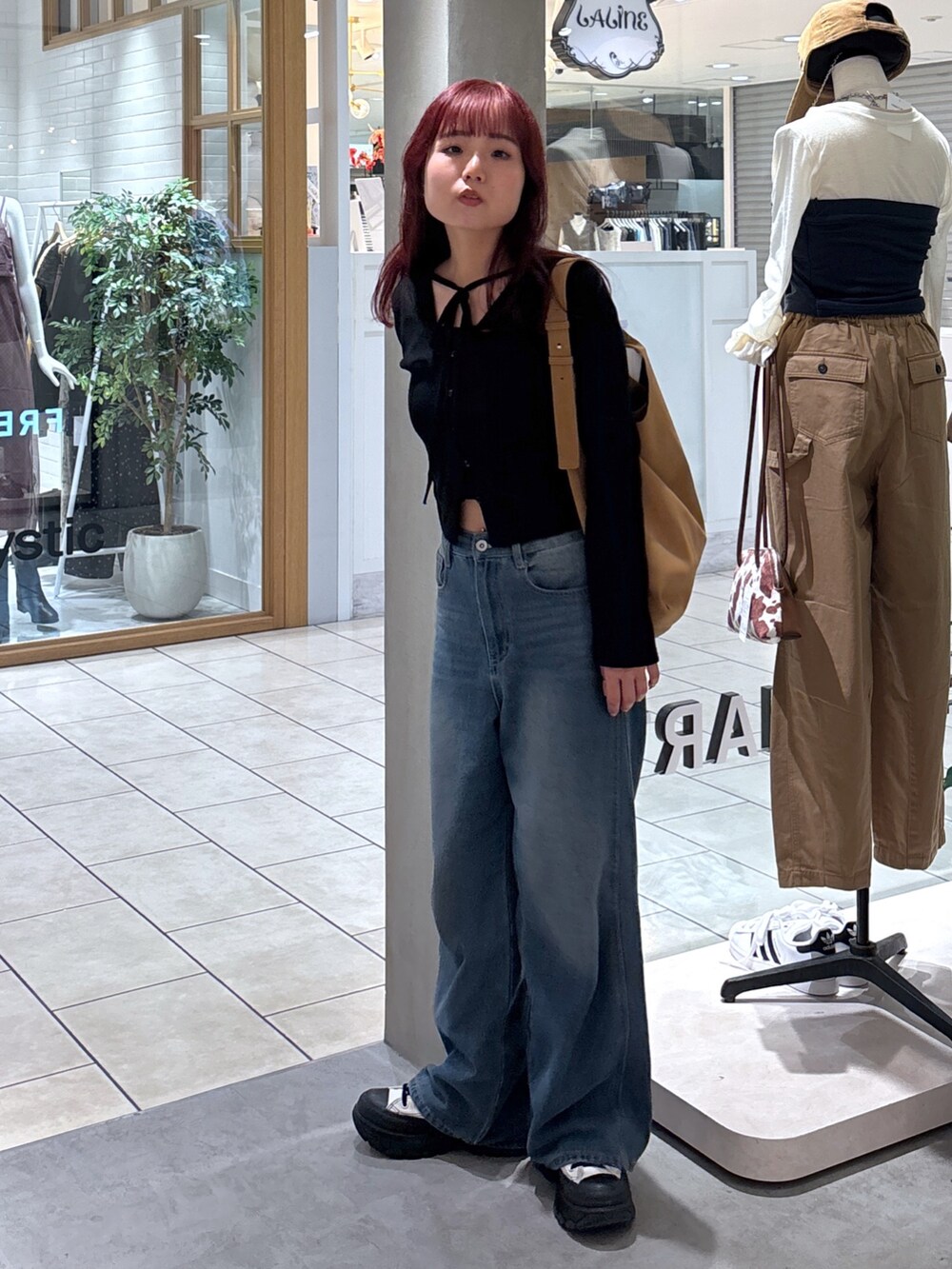 ブラック系のニット/セーター、ホワイト系のキャミソール、ブルー系のデニムパンツを着用したレディースの秋コーディネートの5枚目の写真