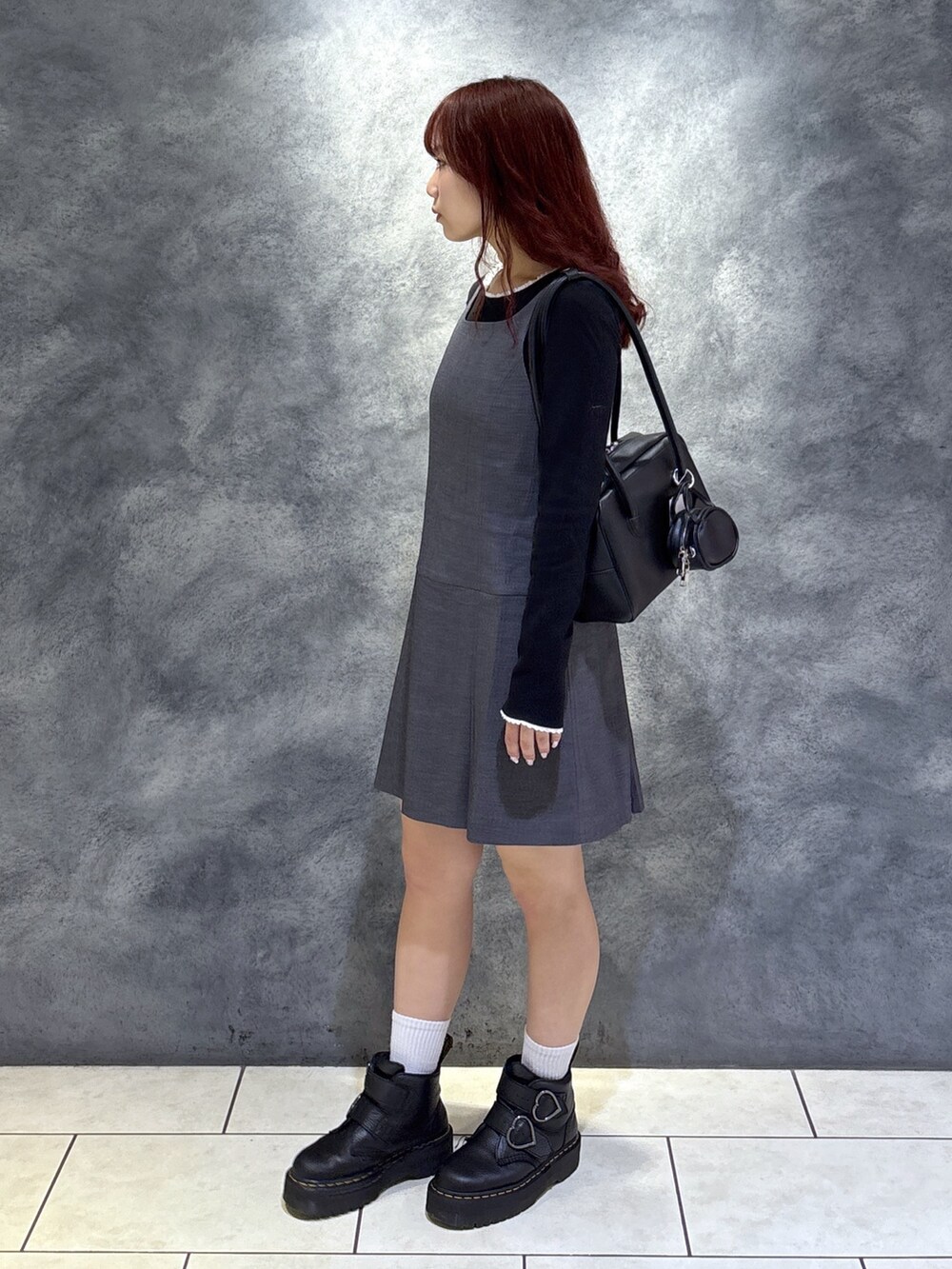 ブラック系のTシャツ/カットソー、ブラック系のブーツ、グレー系のジャンパースカートを着用したレディースの秋コーディネートの5枚目の写真