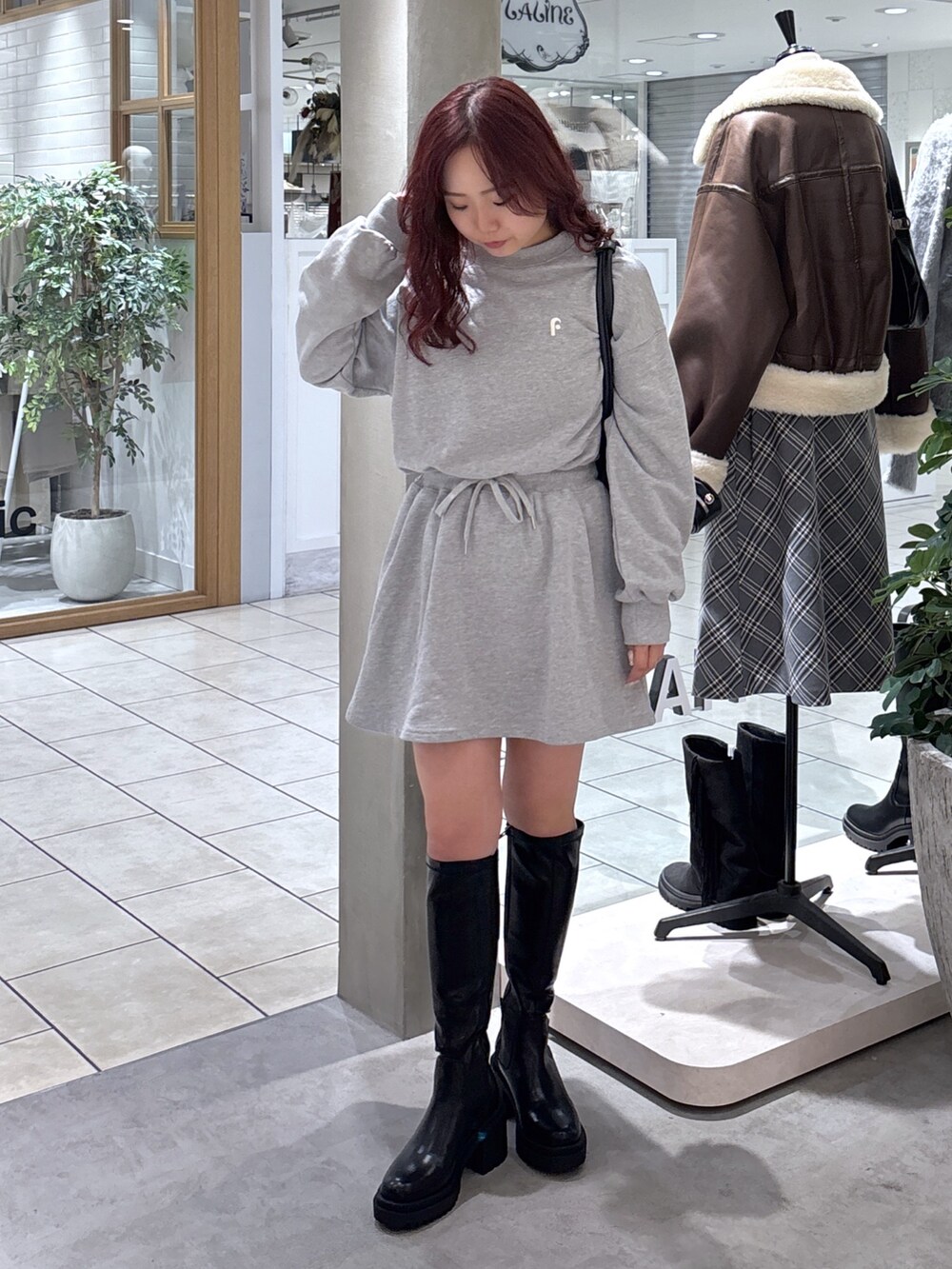 グレー系のワンピース、ブラック系のトートバッグ、ブラック系のブーツを着用したレディースの秋コーディネートの3枚目の写真