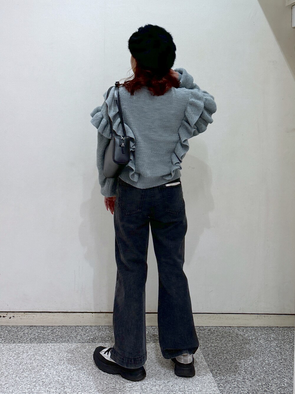 ブルー系のニット/セーター、ブラック系のデニムパンツ、ブラック系のショルダーバッグを着用したレディースの冬コーディネートの5枚目の写真