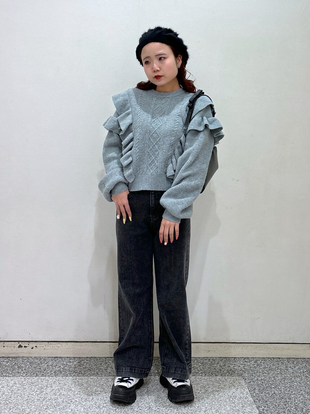 ブルー系のニット/セーター、ブラック系のデニムパンツ、ブラック系のショルダーバッグを着用したレディースの冬コーディネートの2枚目の写真