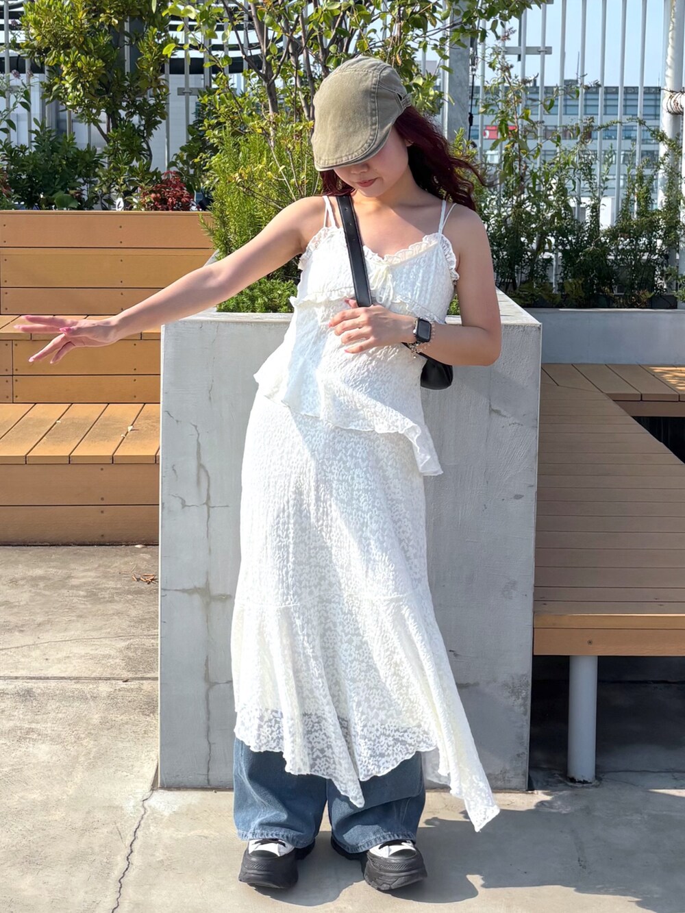 ホワイト系のワンピース、ブルー系のデニムパンツ、ホワイト系のスニーカーを着用したレディースの夏コーディネートの2枚目の写真