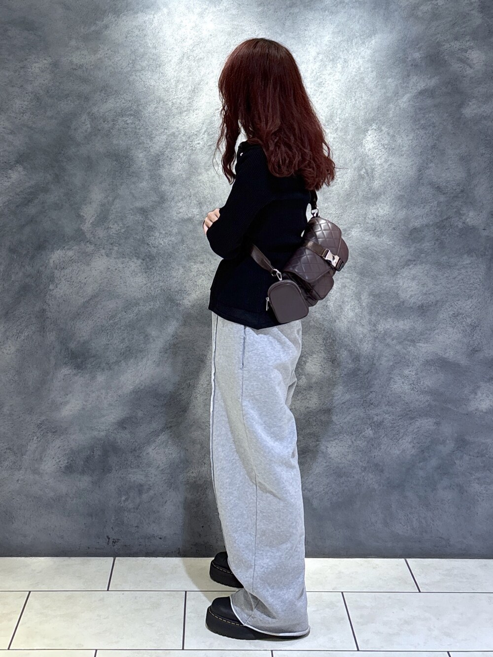 ブラック系のニット/セーター、ブラウン系のショルダーバッグ、ブラック系のブーツを着用したレディースの秋コーディネートの6枚目の写真