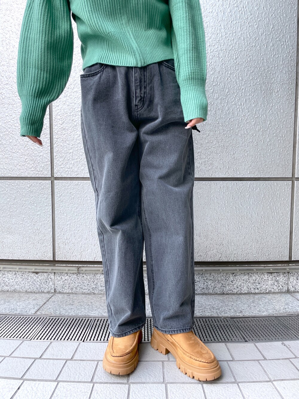 ブラック系のデニムパンツ、グリーン系のカーディガン/ボレロ、ブラウン系のブーツを着用したレディースの秋コーディネートの4枚目の写真