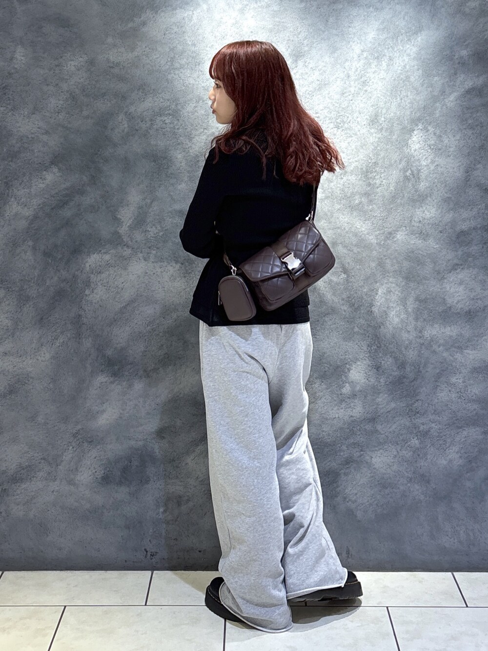 ブラック系のニット/セーター、ブラウン系のショルダーバッグ、ブラック系のブーツを着用したレディースの秋コーディネートの7枚目の写真