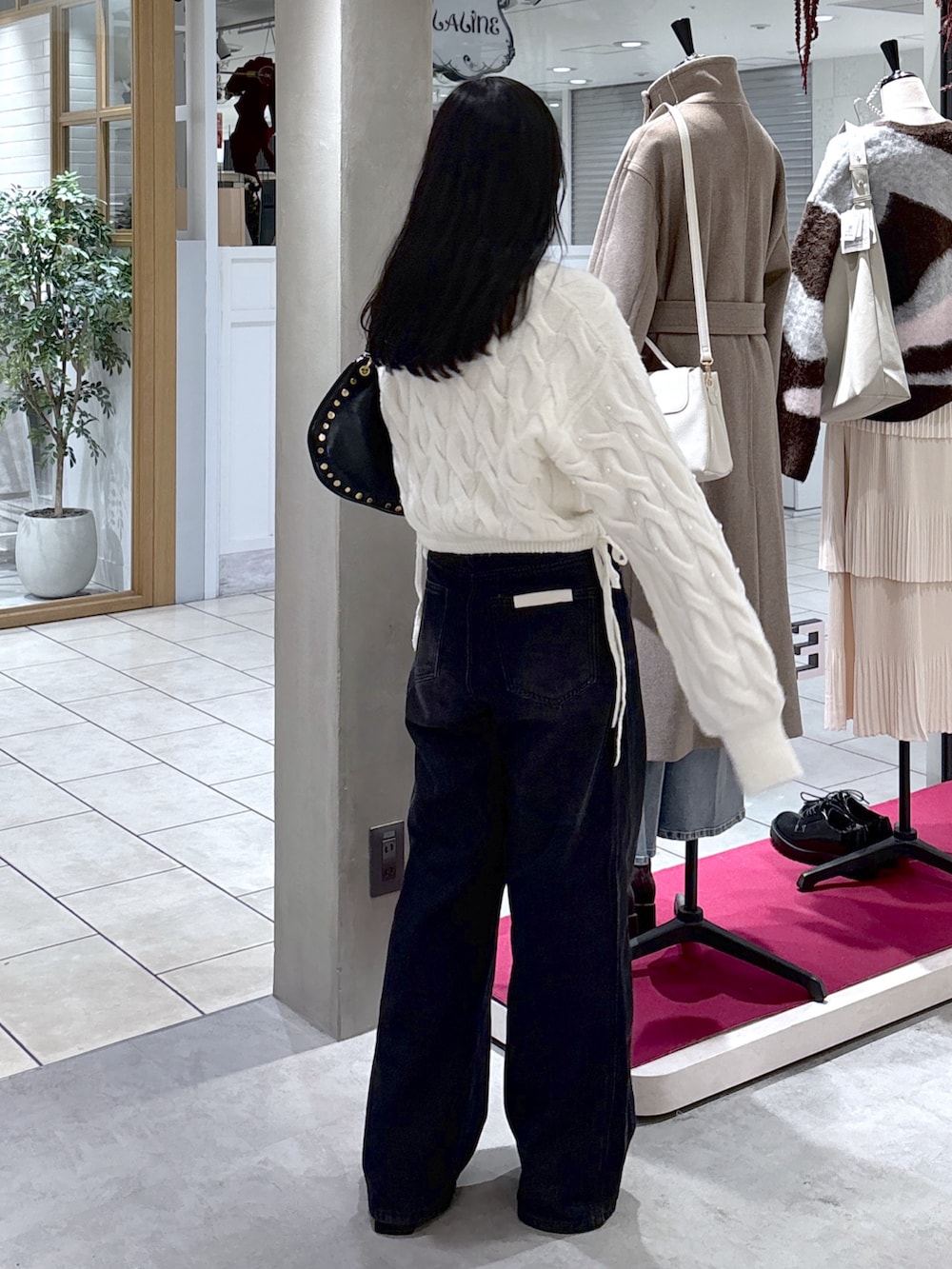 ホワイト系のニット/セーター、ブラック系のデニムパンツ、ブラック系のブーツを着用したレディースの冬コーディネートの9枚目の写真