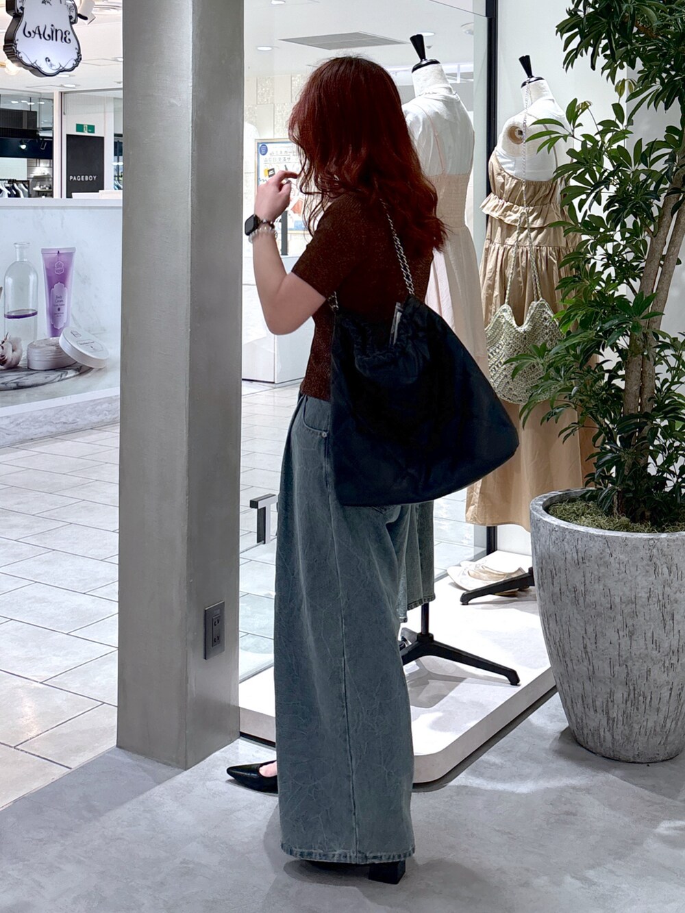 ブルー系のデニムパンツ、ブラック系のパンプス、ブラック系のトートバッグを着用したレディースの夏コーディネートの4枚目の写真