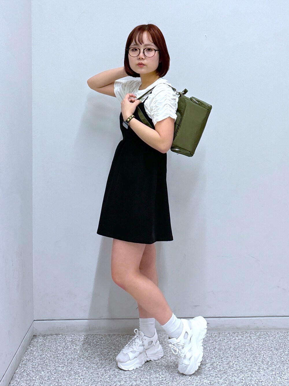 ブラック系のワンピース、グリーン系のショルダーバッグ、ホワイト系のサンダルを着用したレディースの春コーディネートの3枚目の写真