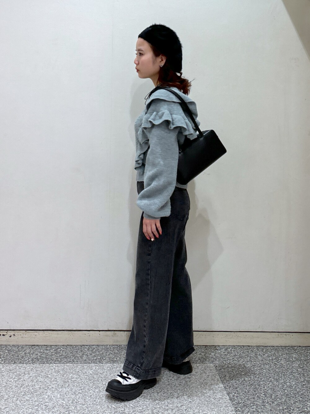 ブルー系のニット/セーター、ブラック系のデニムパンツ、ブラック系のショルダーバッグを着用したレディースの冬コーディネートの3枚目の写真