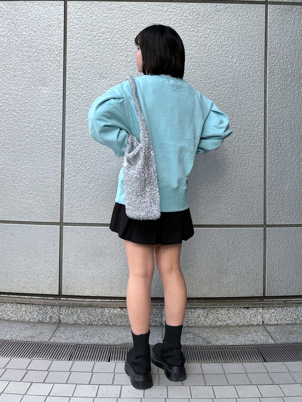 ブラック系のスカート、ブルー系のスウェット、シルバー系のトートバッグを着用したレディースの冬コーディネートの3枚目の写真