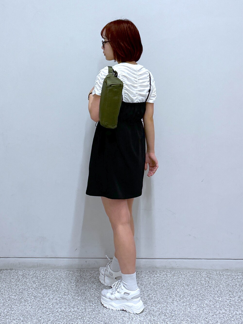 ブラック系のワンピース、グリーン系のショルダーバッグ、ホワイト系のサンダルを着用したレディースの春コーディネートの4枚目の写真