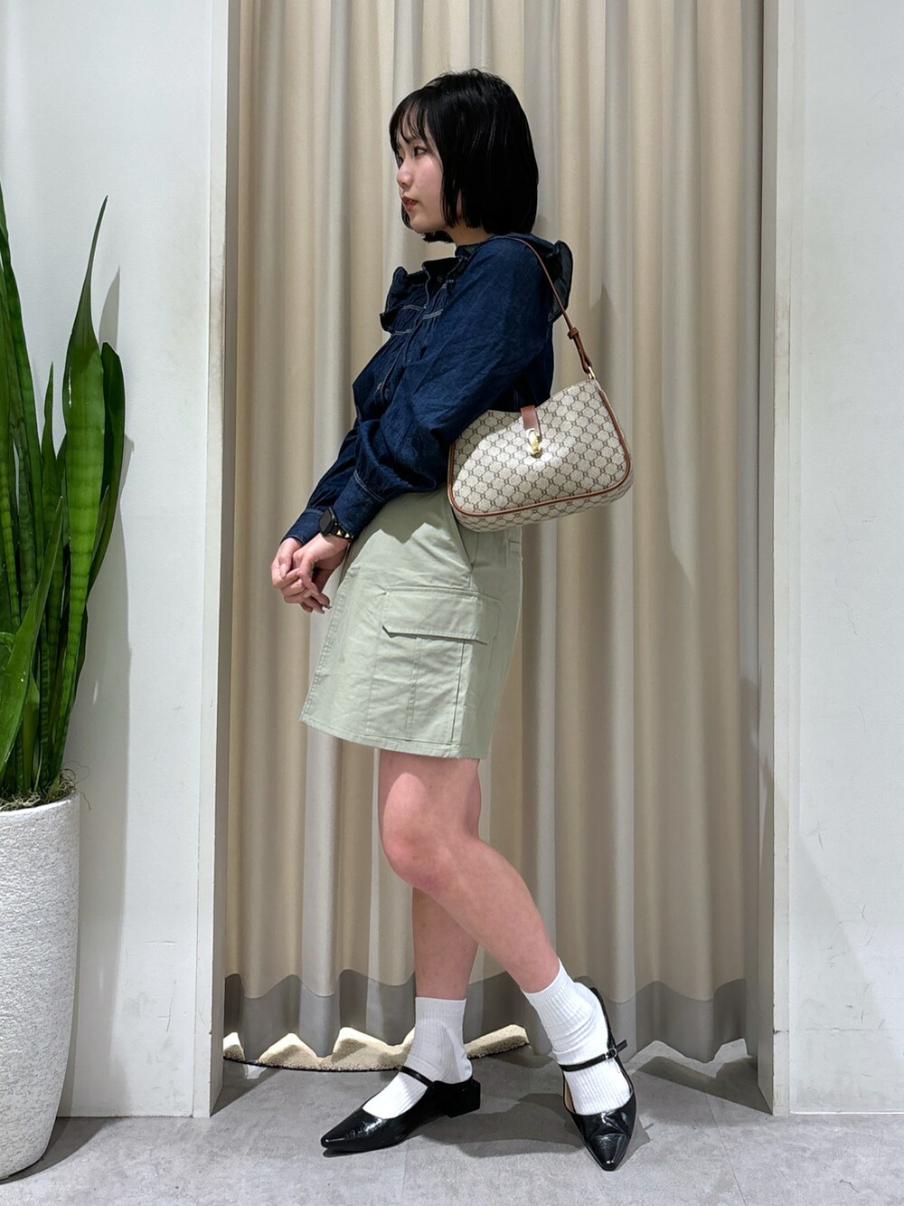 ブルー系のシャツ/ブラウス、グリーン系のスカート、ブラック系のパンプスを着用したレディースの春コーディネートの2枚目の写真