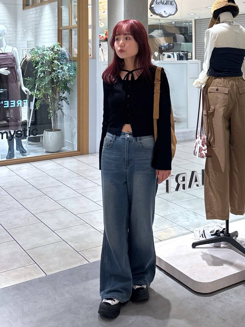 ブラック系のニット/セーター、ホワイト系のキャミソール、ブルー系のデニムパンツを着用したレディースの秋コーディネートの4枚目の写真