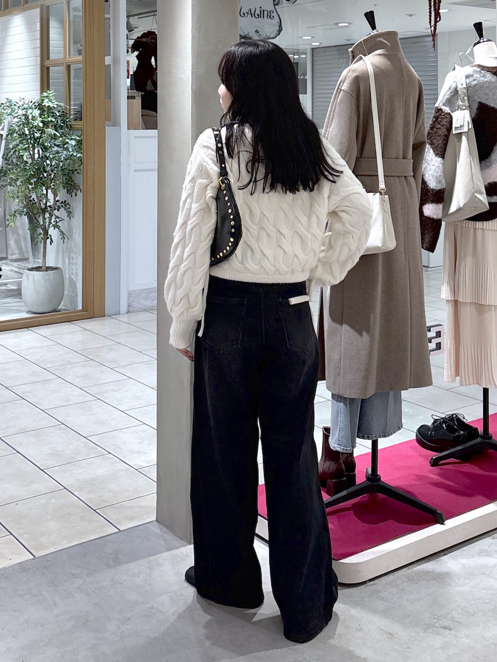 ホワイト系のニット/セーター、ブラック系のデニムパンツ、ブラック系のブーツを着用したレディースの冬コーディネートの8枚目の写真