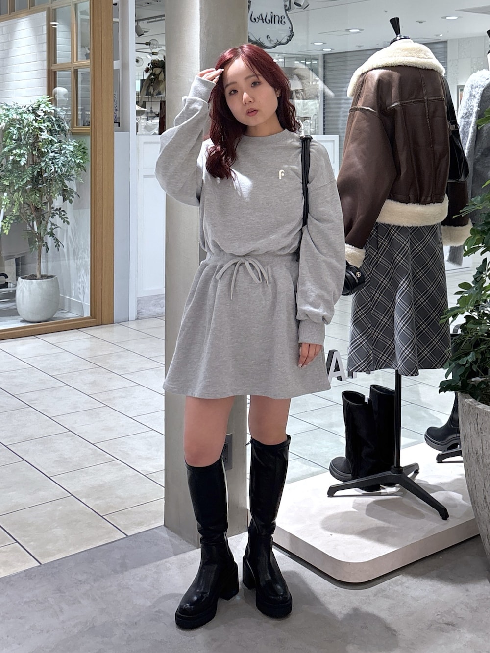 グレー系のワンピース、ブラック系のトートバッグ、ブラック系のブーツを着用したレディースの秋コーディネートの2枚目の写真