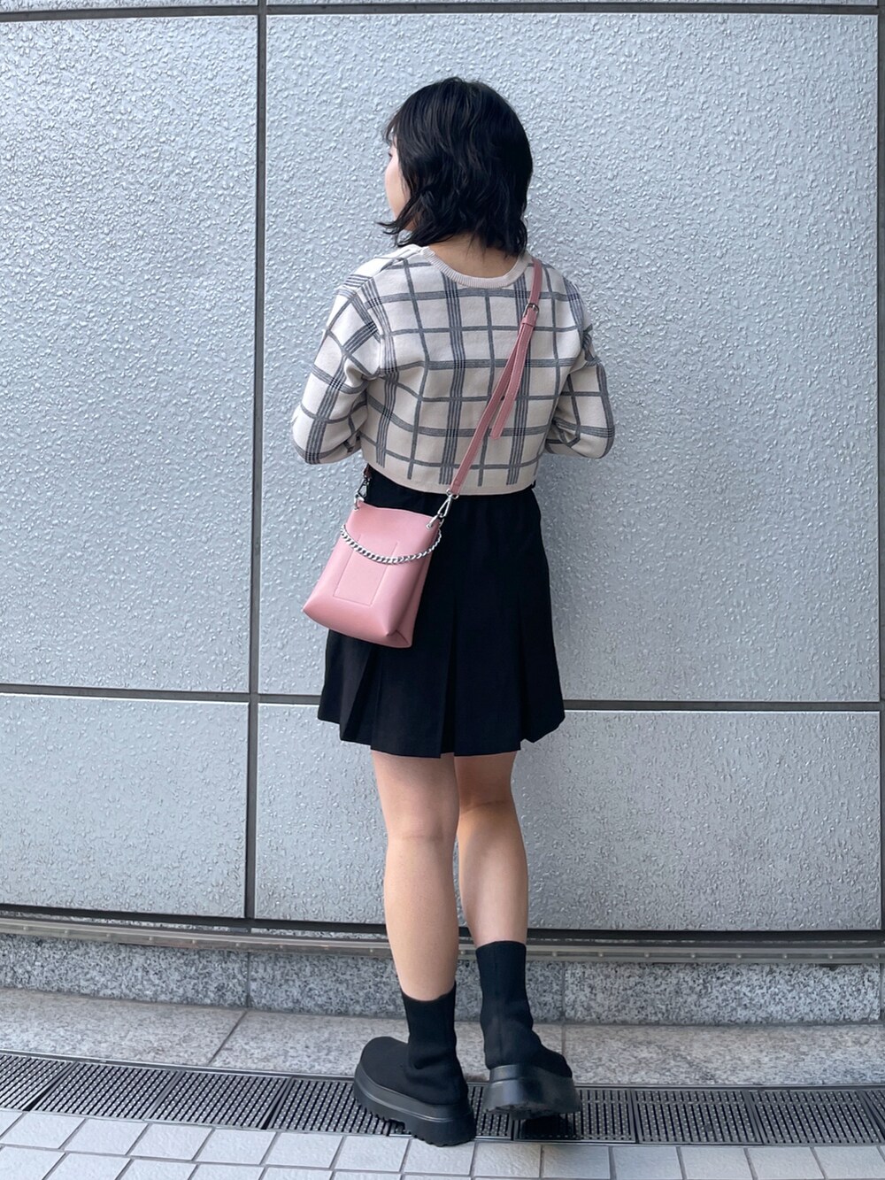 ブラック系のスカート、ホワイト系のニット/セーター、ピンク系のショルダーバッグを着用したレディースの冬コーディネートの3枚目の写真