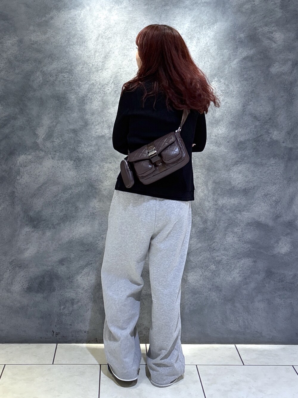 ブラック系のニット/セーター、ブラウン系のショルダーバッグ、ブラック系のブーツを着用したレディースの秋コーディネートの9枚目の写真