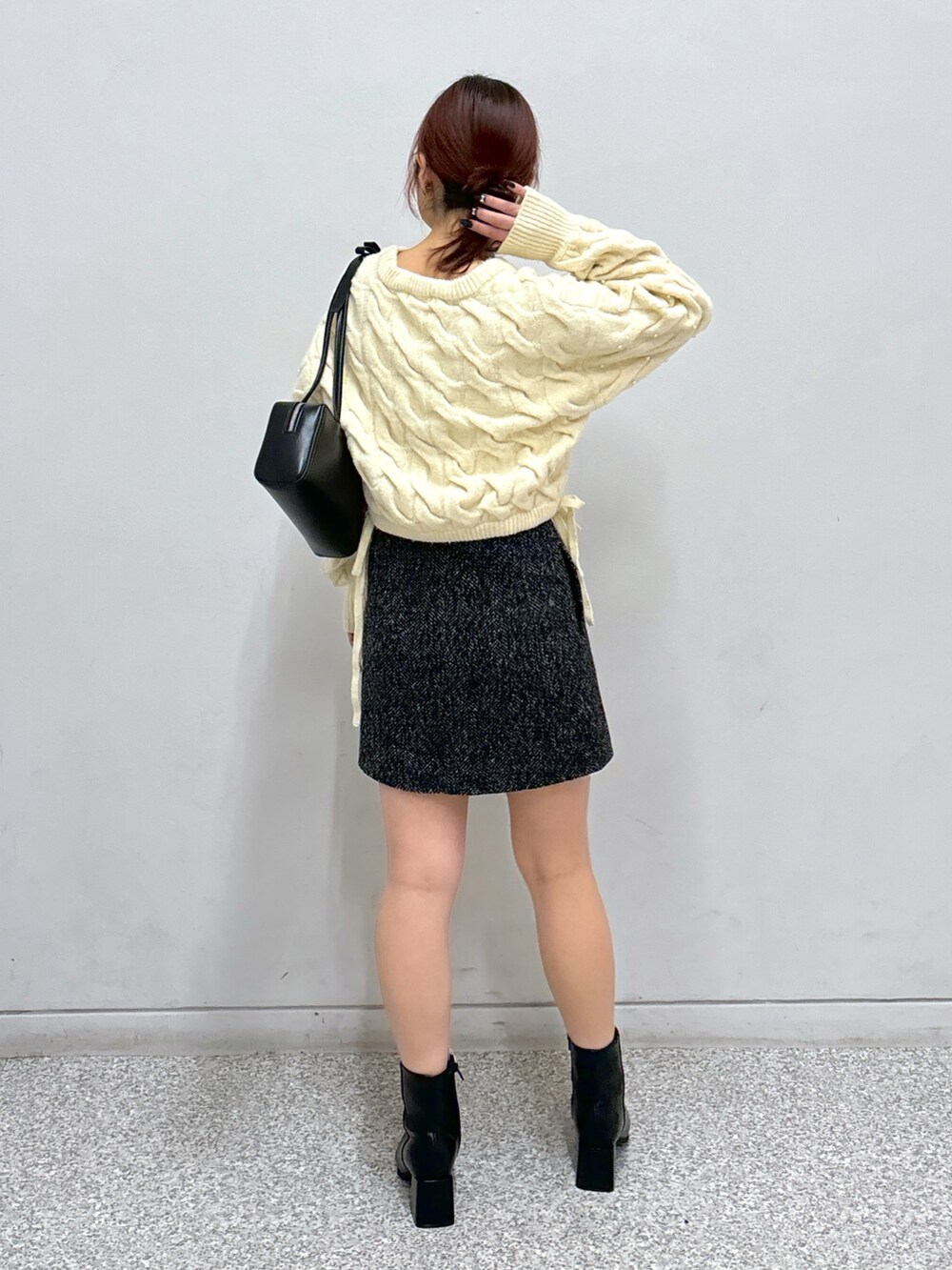 ホワイト系のニット/セーター、ブラック系のスカート、ブラック系のブーツを着用したレディースの冬コーディネートの5枚目の写真