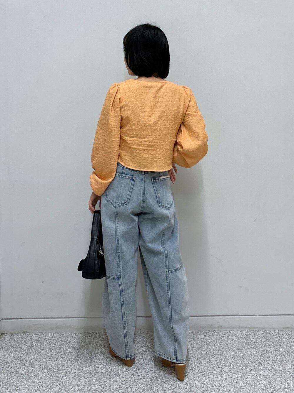 ブルー系のデニムパンツ、オレンジ系のシャツ/ブラウス、ベージュ系のパンプスを着用したレディースの春コーディネートの4枚目の写真