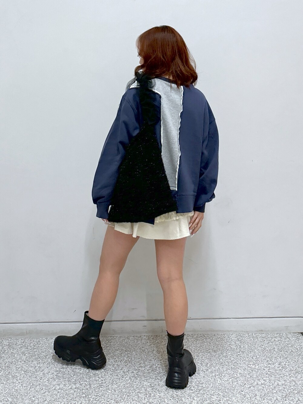 ブルー系のスウェット、ホワイト系のスカート、ブラック系のショルダーバッグを着用したレディースの秋コーディネートの5枚目の写真