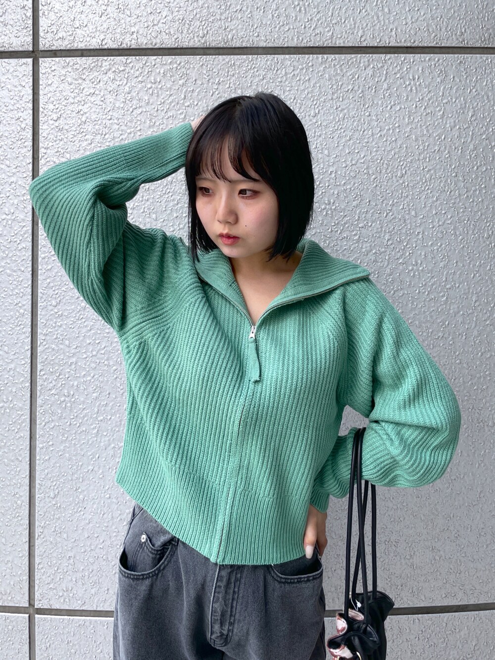 ブラック系のデニムパンツ、グリーン系のカーディガン/ボレロ、ブラウン系のブーツを着用したレディースの秋コーディネートの3枚目の写真