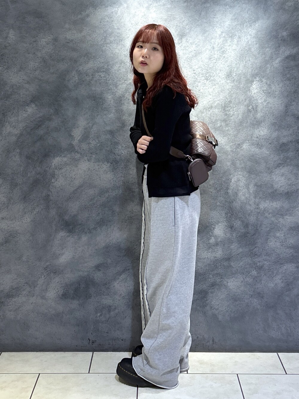 ブラック系のニット/セーター、ブラウン系のショルダーバッグ、ブラック系のブーツを着用したレディースの秋コーディネートの4枚目の写真