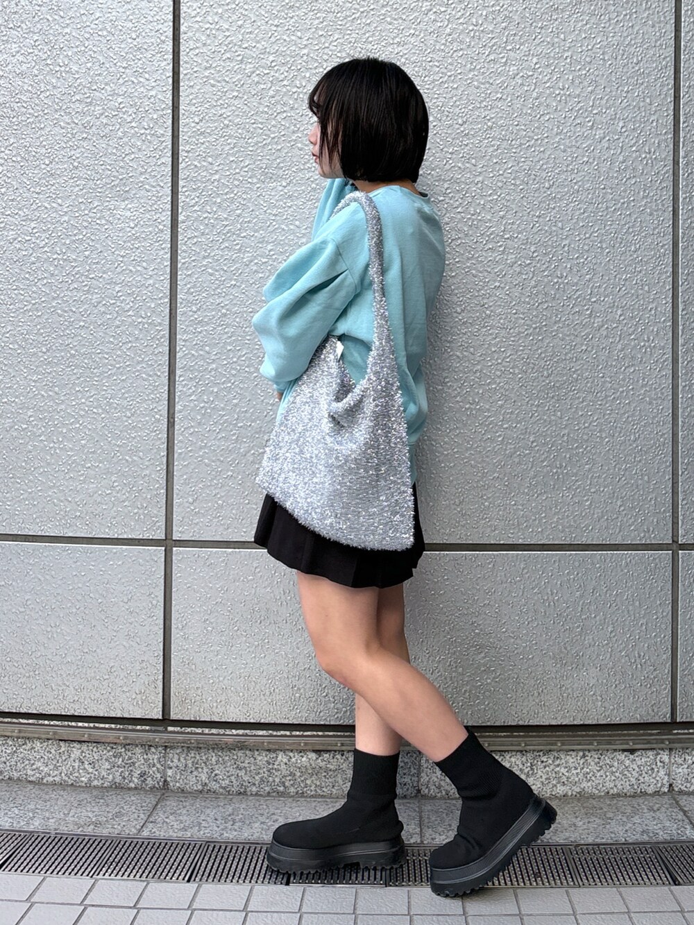 ブラック系のスカート、ブルー系のスウェット、シルバー系のトートバッグを着用したレディースの冬コーディネートの2枚目の写真