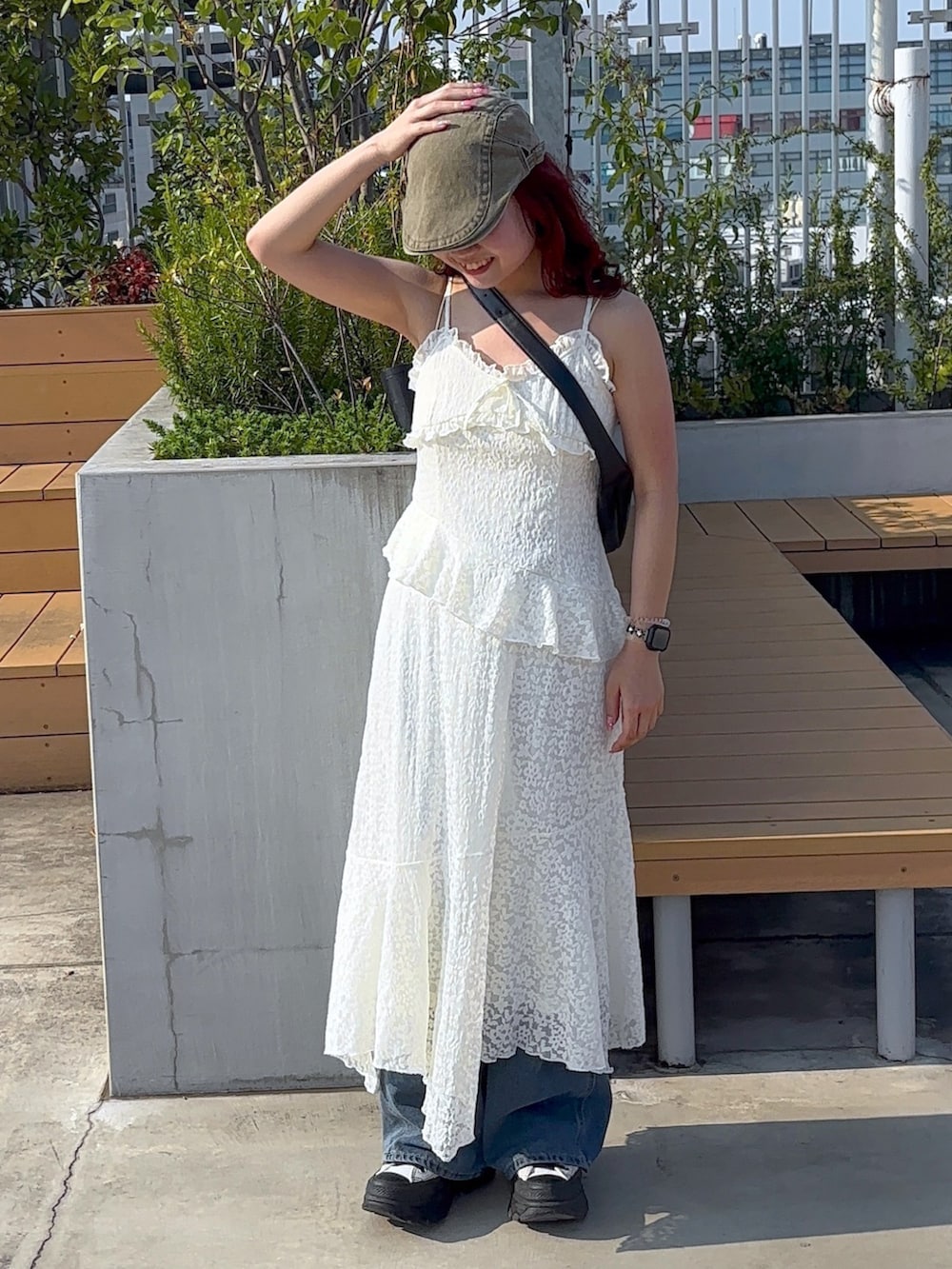 ホワイト系のワンピース、ブルー系のデニムパンツ、ホワイト系のスニーカーを着用したレディースの夏コーディネートの3枚目の写真