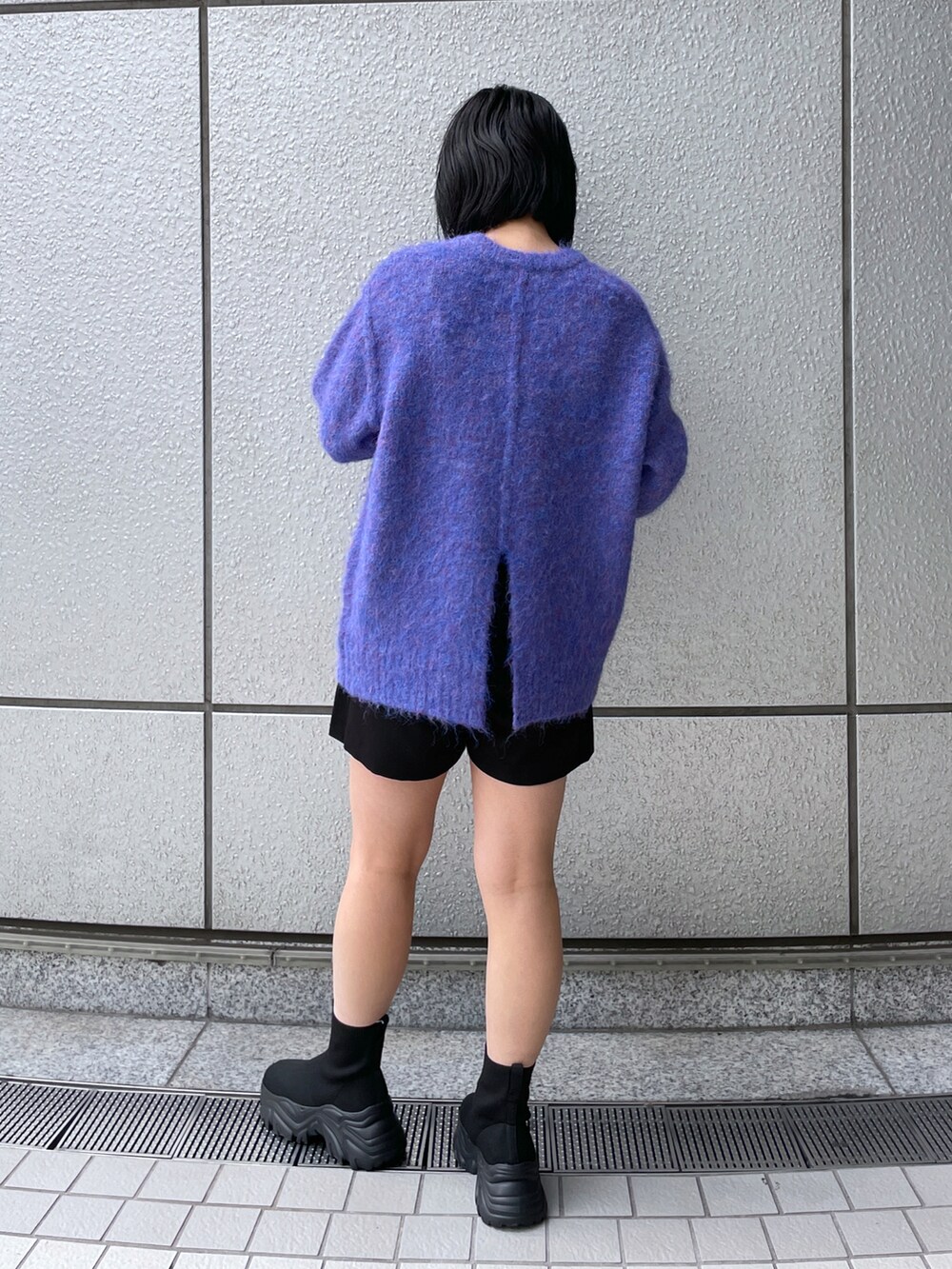 ブルー系のニット/セーター、ブラック系のその他パンツ、ブラック系のブーツを着用したレディースの秋コーディネートの3枚目の写真