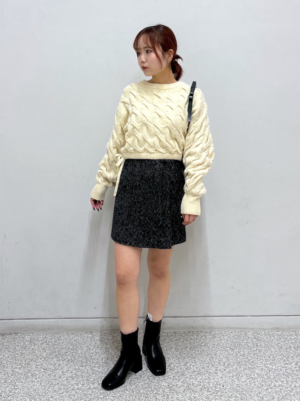 ホワイト系のニット/セーター、ブラック系のスカート、ブラック系のブーツを着用したレディースの冬コーディネートの2枚目の写真