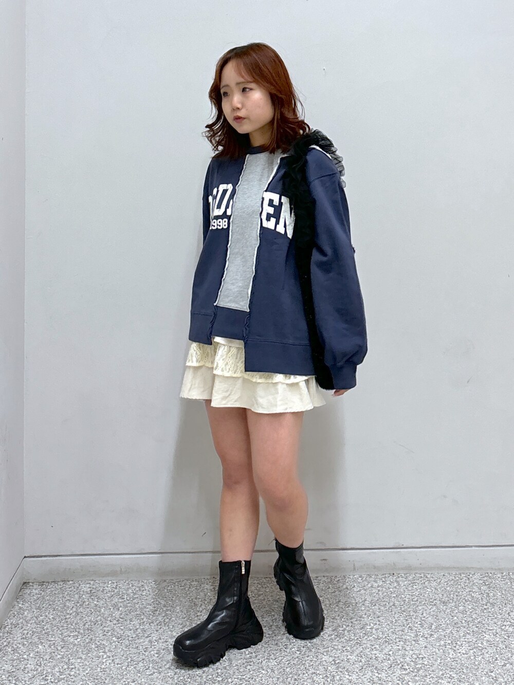 ブルー系のスウェット、ホワイト系のスカート、ブラック系のショルダーバッグを着用したレディースの秋コーディネートの2枚目の写真