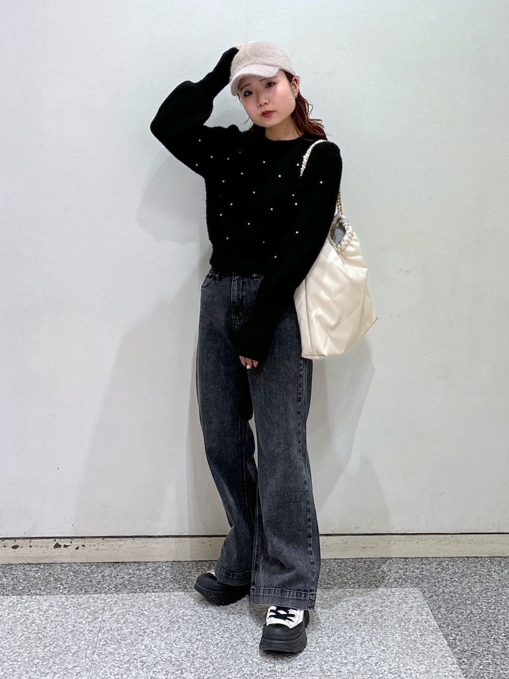 ブラック系のニット/セーター、ブラック系のデニムパンツ、ホワイト系のスニーカーを着用したレディースの冬コーディネートの2枚目の写真