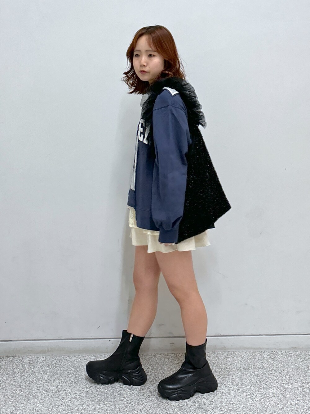 ブルー系のスウェット、ホワイト系のスカート、ブラック系のショルダーバッグを着用したレディースの秋コーディネートの3枚目の写真