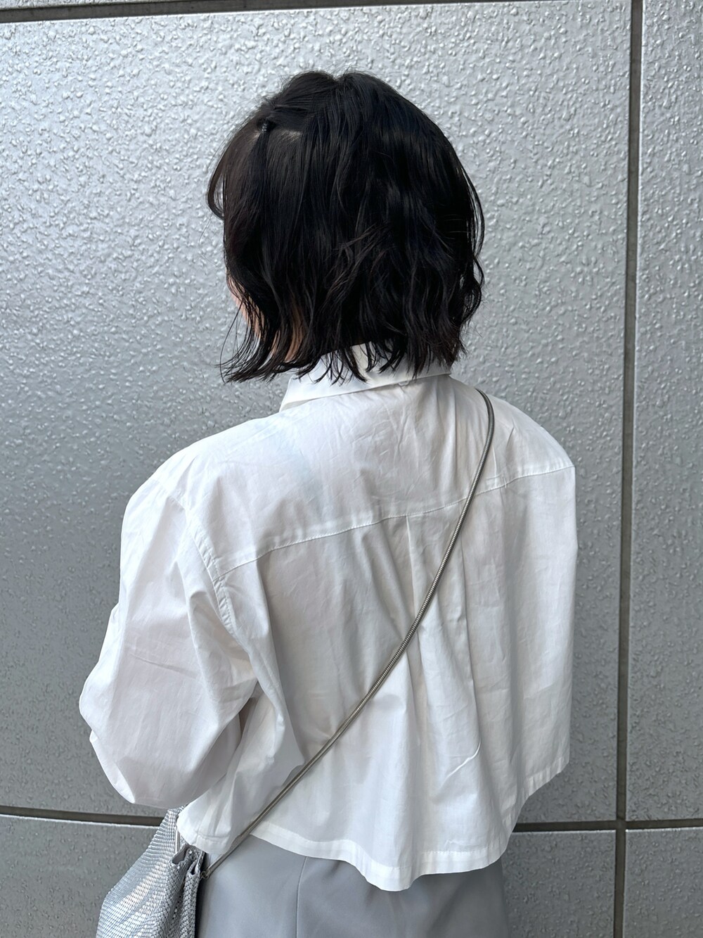 グレー系のスカート、ホワイト系のシャツ/ブラウス、シルバー系のハンドバッグを着用したレディースの冬コーディネートの5枚目の写真