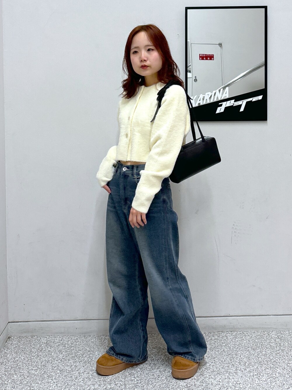 ホワイト系のカーディガン/ボレロ、ブラック系のショルダーバッグ、ブルー系のデニムパンツを着用したレディースの冬コーディネートの2枚目の写真