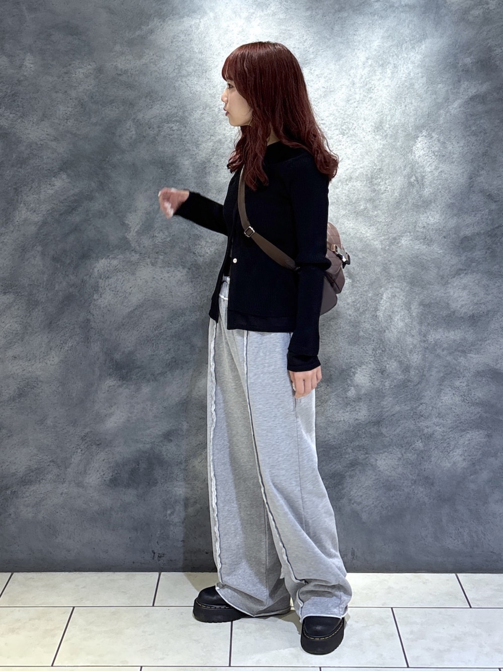 ブラック系のニット/セーター、ブラウン系のショルダーバッグ、ブラック系のブーツを着用したレディースの秋コーディネートの3枚目の写真