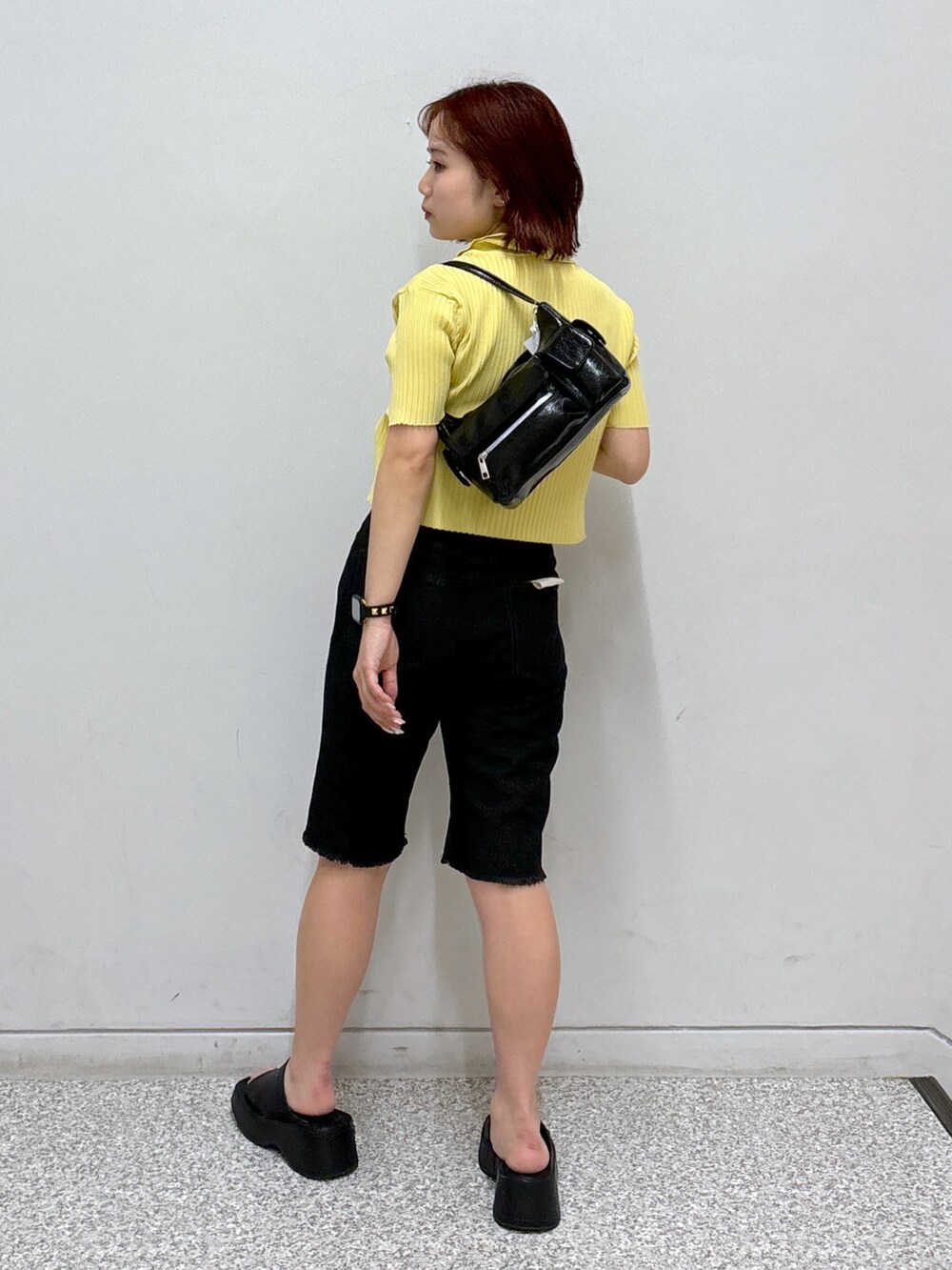 イエロー系のニット/セーター、ブラック系のデニムパンツ、ホワイト系のハンドバッグを着用したレディースの夏コーディネートの4枚目の写真