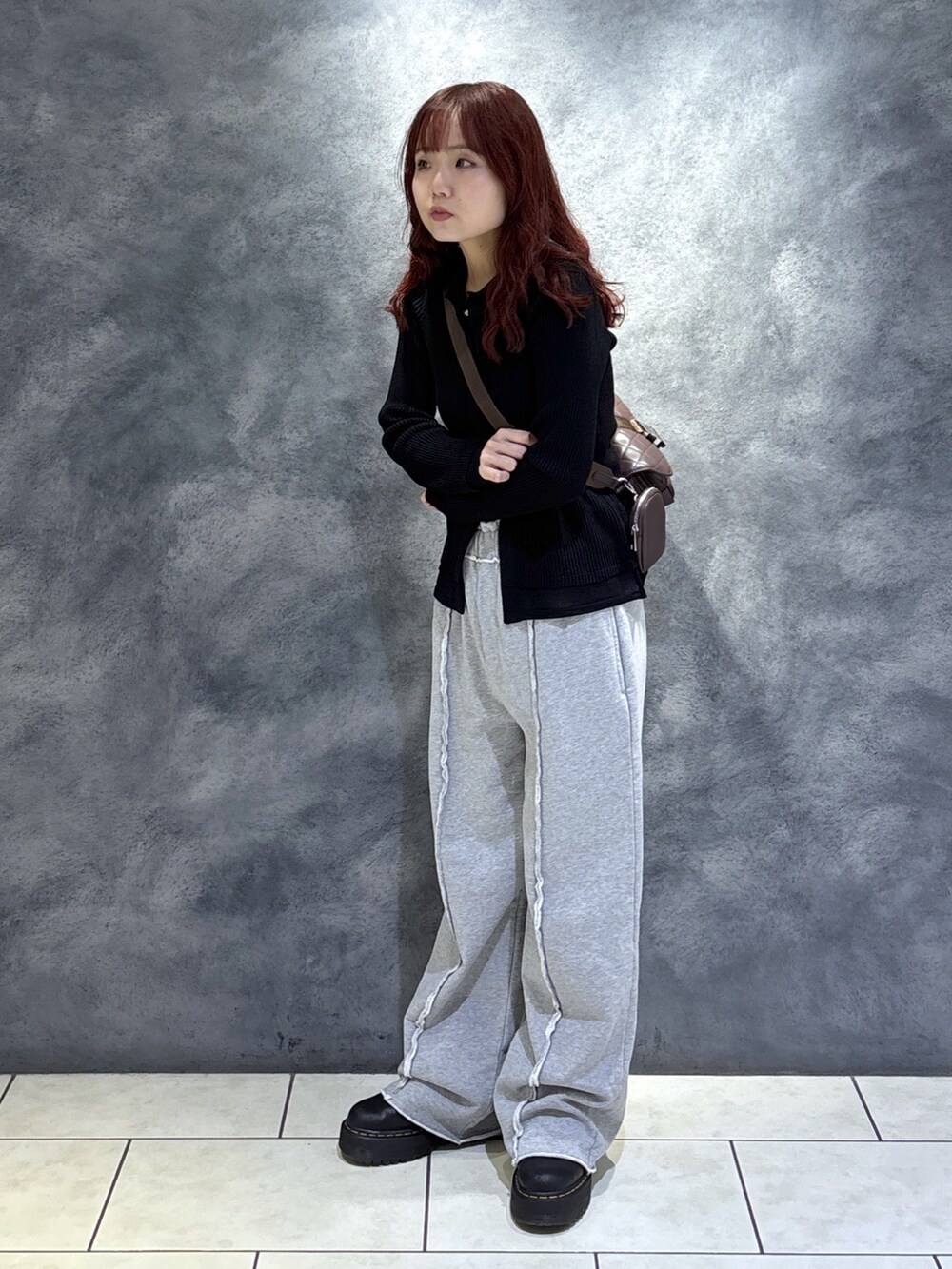 ブラック系のニット/セーター、ブラウン系のショルダーバッグ、ブラック系のブーツを着用したレディースの秋コーディネートの2枚目の写真