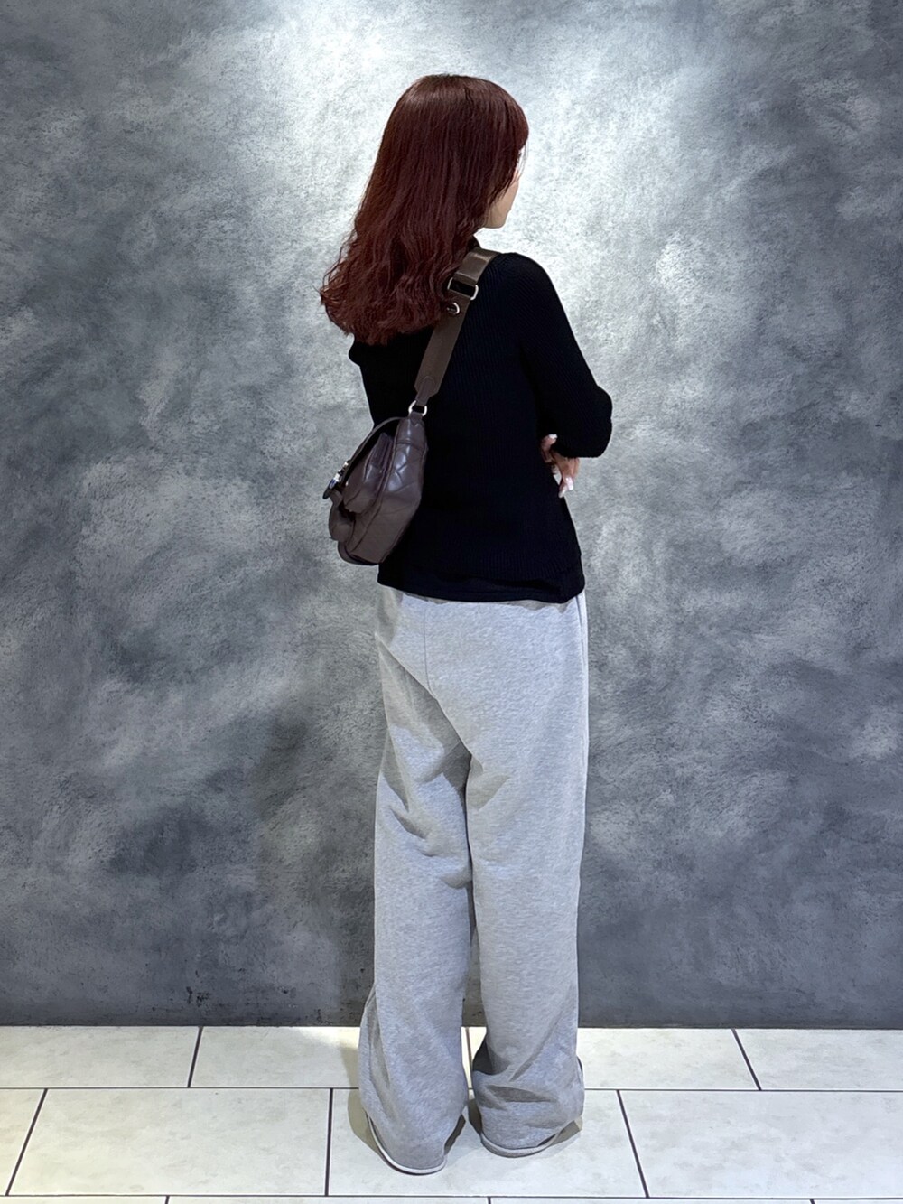 ブラック系のニット/セーター、ブラウン系のショルダーバッグ、ブラック系のブーツを着用したレディースの秋コーディネートの10枚目の写真