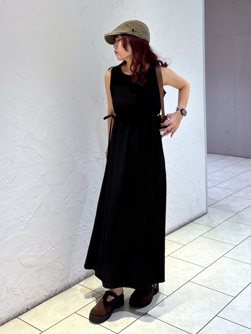 ブラック系のワンピース、ブラウン系のハンドバッグ、ホワイト系のキャミソールを着用したレディースの夏コーディネートの3枚目の写真