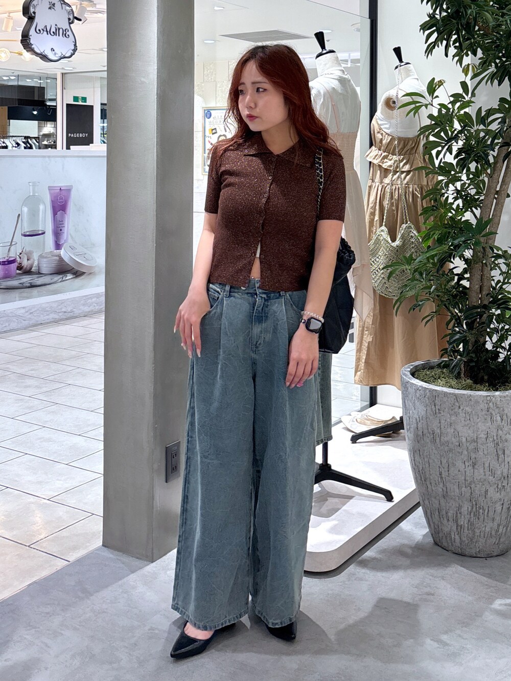 ブルー系のデニムパンツ、ブラック系のパンプス、ブラック系のトートバッグを着用したレディースの夏コーディネートの2枚目の写真
