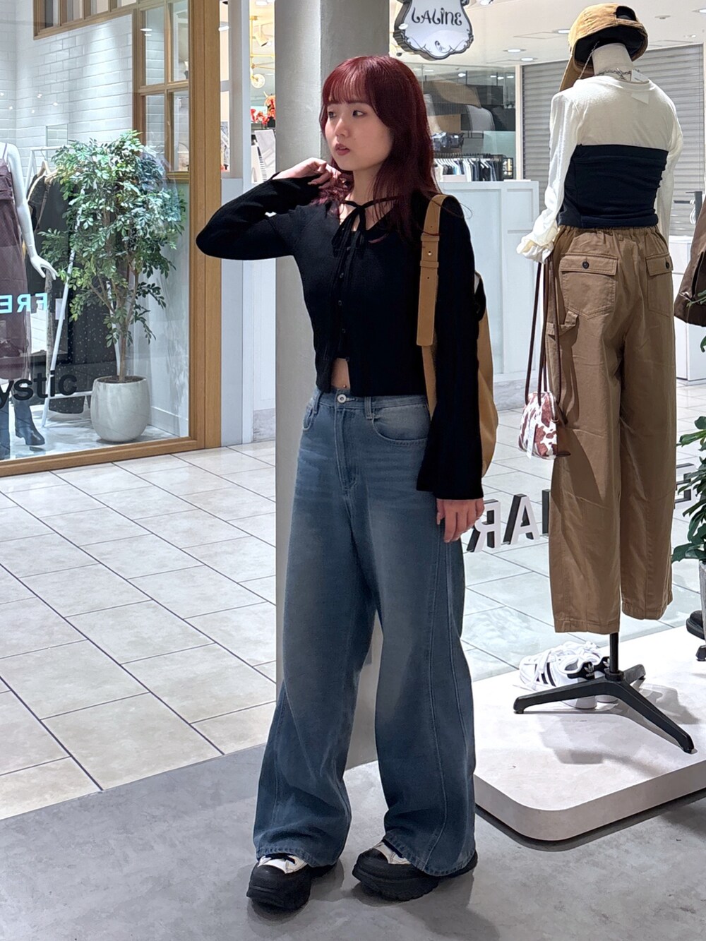 ブラック系のニット/セーター、ホワイト系のキャミソール、ブルー系のデニムパンツを着用したレディースの秋コーディネートの6枚目の写真