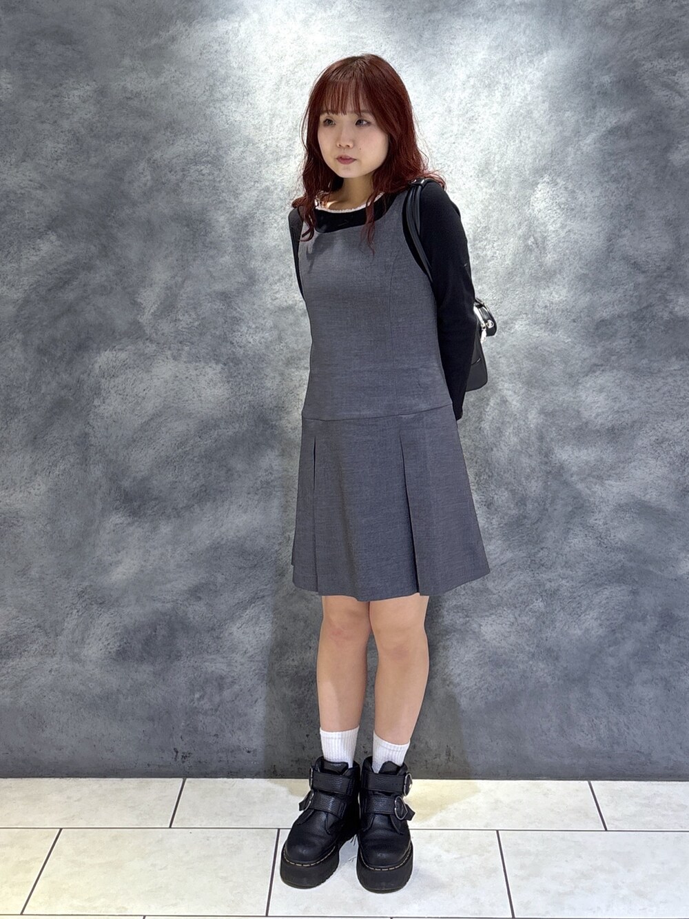 ブラック系のTシャツ/カットソー、ブラック系のブーツ、グレー系のジャンパースカートを着用したレディースの秋コーディネートの3枚目の写真