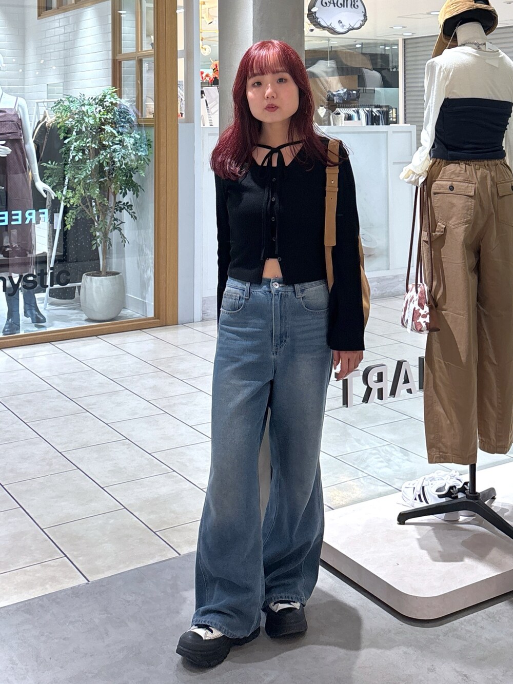 ブラック系のニット/セーター、ホワイト系のキャミソール、ブルー系のデニムパンツを着用したレディースの秋コーディネートの3枚目の写真