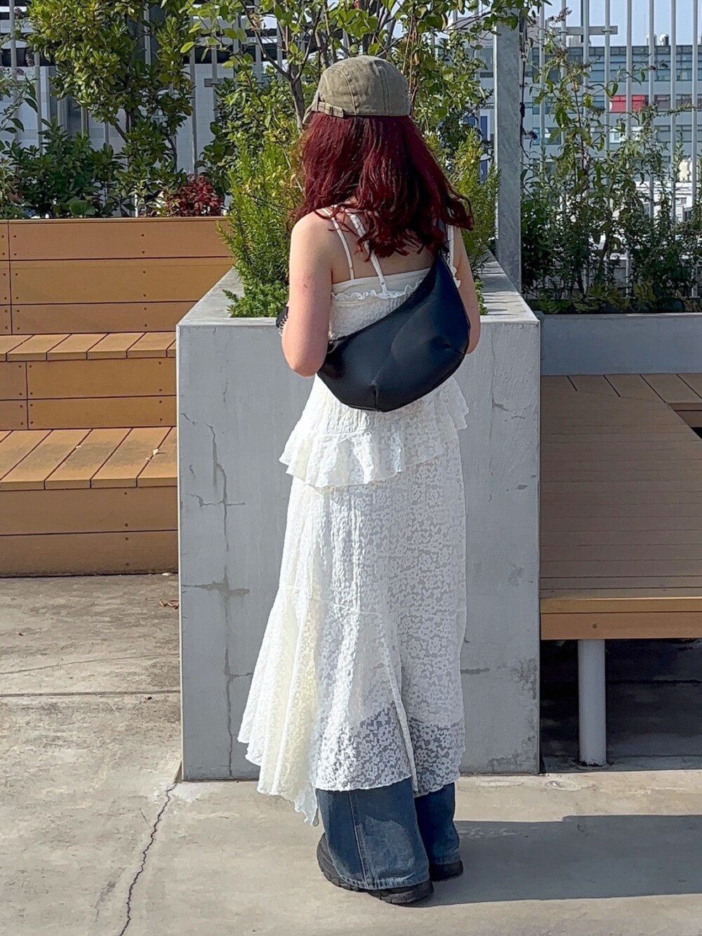 ホワイト系のワンピース、ブルー系のデニムパンツ、ホワイト系のスニーカーを着用したレディースの夏コーディネートの6枚目の写真