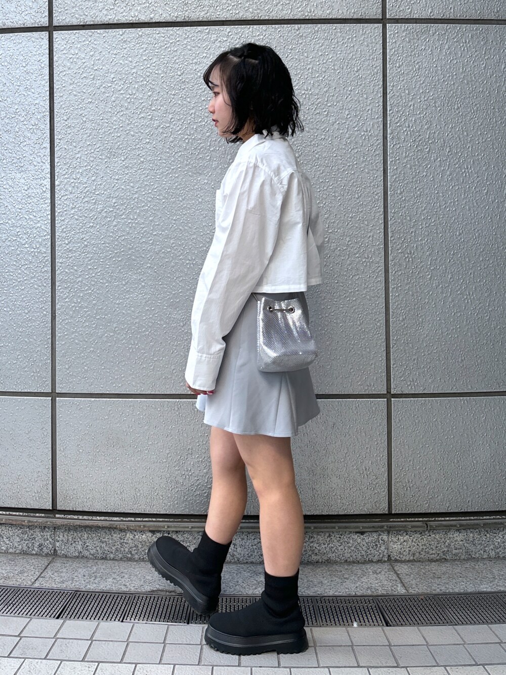 グレー系のスカート、ホワイト系のシャツ/ブラウス、シルバー系のハンドバッグを着用したレディースの冬コーディネートの2枚目の写真